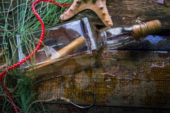 a bottle of shipwreck lies caught on an old wooden wet brown deck