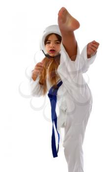 karate girl in a protective helmet with a blue belt and a white kimono kicks forward
