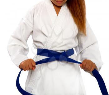 little karate girl in a white kimono ties a new blue belt
