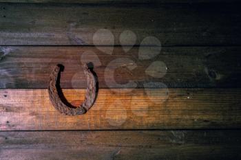 very old and rusty steel classic horseshoe lying on a dark wooden background