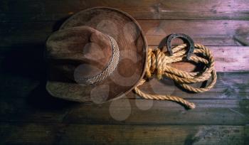 steel classic horseshoe cowboy hat and coarse rope on a dark wooden background top view