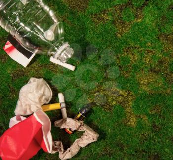 empty bottles of batteries and other household rubbish thrown out by unconscious people onto green grass in nature