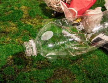 empty bottles of batteries and other household rubbish thrown out by unconscious people onto green grass in nature