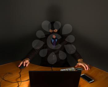 representative businessman in a suit and tie, but in a mask with a balaclava covering his face, is engaged in theft through the Internet from a laptop