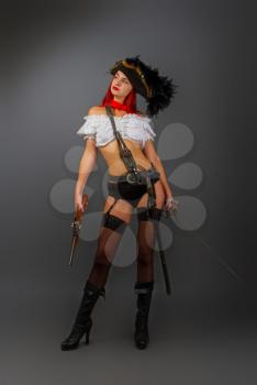 Bright armed sexy girl the pirate captain in a cocked hat stands in underwear and stockings and a short white blouse on a dark background