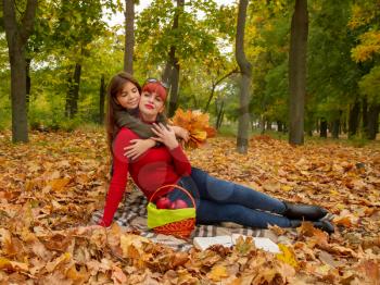 young mother and little daughters in bright sweaters on a picnic in nature relax