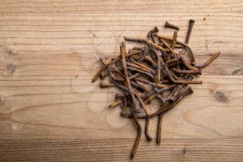 a lot of old rusty bent nails lying on a wooden board