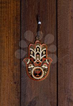 protective amulet Hamsa Fatima hand with a beautiful pattern hanging on a rough wooden door