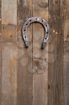 an old horse horseshoe nailed happily by a rusty nail to a wooden wall