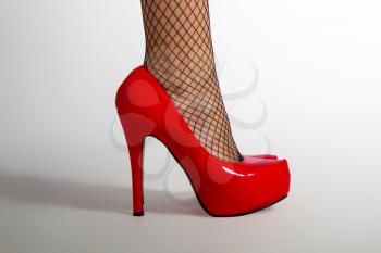 young girl in fishnet tights and red high-heeled shoes