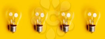 four old classic incandescent bulbs on a bright yellow background