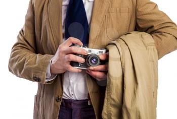 retro paparazzi in a suit and tie secretly takes a photo on a film camera hiding in a coat
