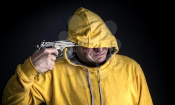 a man in a bright yellow hooded sweatshirt is about to attempt a suicide by gun
