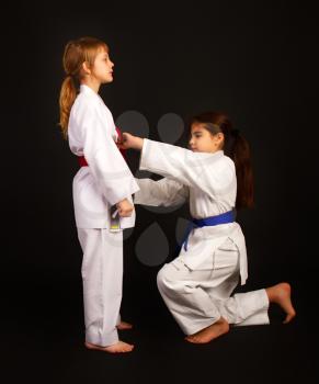 one more experienced karate girl helps another tie a kimono belt correctly
