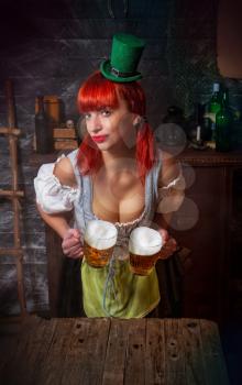 young red-haired Irish waitress in a little leprechaun hat brings two glasses of foamy beer in a St. Patrick's Day pub