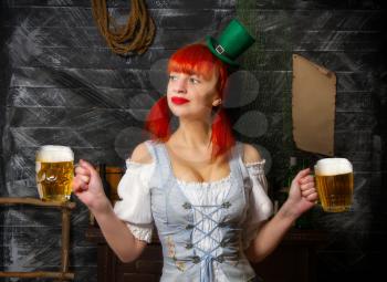 young red-haired Irish waitress in a little leprechaun hat brings two glasses of foamy beer in a St. Patrick's Day pub