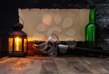 vintage horizontal scroll with place for text on a dark wooden wall steel epee green bottle with alcohol and a lantern with a burning candle