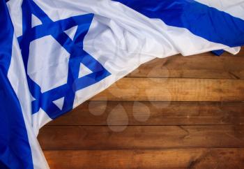 White-blue Israeli state flag with a star of David lies on wooden boards forming a frame for text