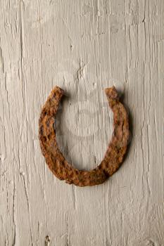 Very old rusty horse horseshoe symbol of good luck lies on a gray wooden surface