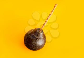 classic round black antique bomb with a non-burning rope wick on a yellow background
