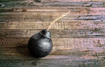 classic round black antique bomb with a non-burning rope wick on a rough wooden background