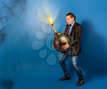 concept man in a business jacket tie and jeans holding a huge old round bomb with a burning wick