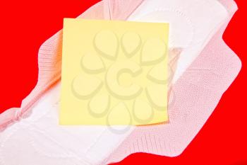 White feminine sanitary pad with empty yellow paper for text on a bright red background