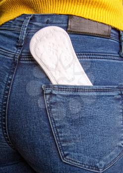 White feminine sanitary pad in a jeans pocket of a young girl