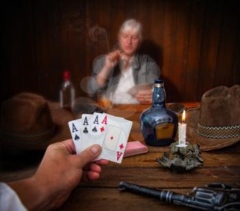 two people in the wild west play cards in the saloon with their revolvers and hats on the table