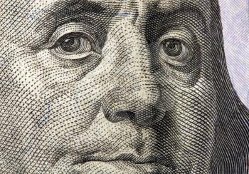 very close-up image of Benjamin Franklin's face on United States of America hundred dollar bill