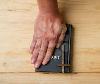 the hand of an adult man lies on the bible as a sign that he is telling the truth