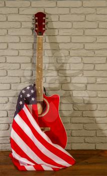 beautiful classical acoustic guitar and stars striped USA flag on gray brick background