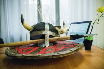 An abstract image of the office desk of the HR Manager HeadHunter Recruitment. With modern laptop and antique helmet with spear and shield