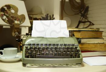 old typewriter with inserted blank sheet of paper on the background of the writer's room