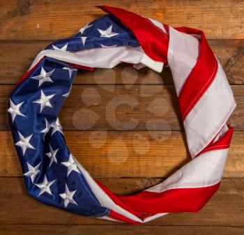 the star-striped flag of the USA lies on a wooden surface rolled into a ring