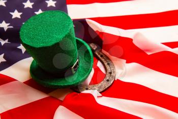 The classic green Leprechaun hat and horseshoe rests on the Stars and Stripes USA banner 