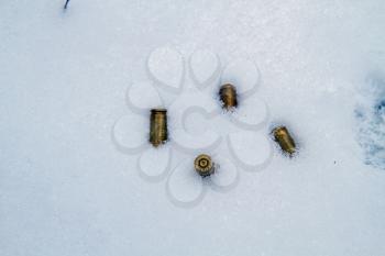 Four used nine-millimeter pistol sleeves lying in the snow 