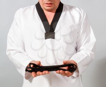 Strong male athlete in white taekwondo kimono receives a well-deserved black belt