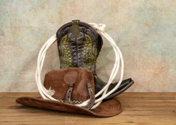 Shabby old ornate classic cowboy boots hat and lasso on vintage background