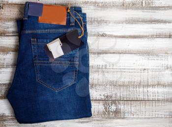 New classic blue jeans with blank labels lie on a rough wooden background as seen from the back pocket 