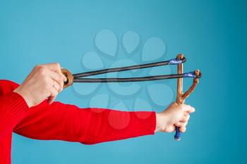 Hands of an adult man who holds a huge homemade slingshot ready to shoot 