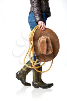 Female legs in leather cowboy boots and blue jeans with wide-brimmed hat and lasso isolated on white background