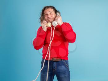 Adult male call center worker in casual clothes answers phone calls very emotionally