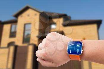 Smart watches with home security app on a hand on the building background