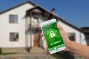 Smartphone with home security app in a hand on the building background