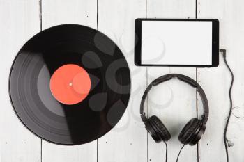 Vintage record LP, smartphone and headphones on the wooden background