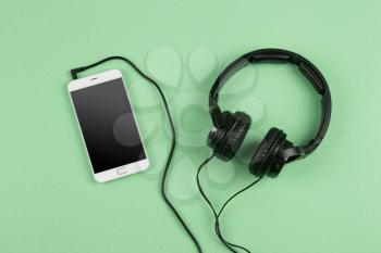 Music online concept - phablet and headphones on the green background
