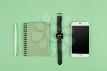 Smartphone, notepad,pen and watch on the color background 