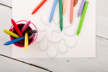 colorful crayons and blank paper on the wooden desk