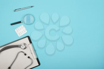 doctors workplace - medical tablet, stethoscope, pills and magnifying glass